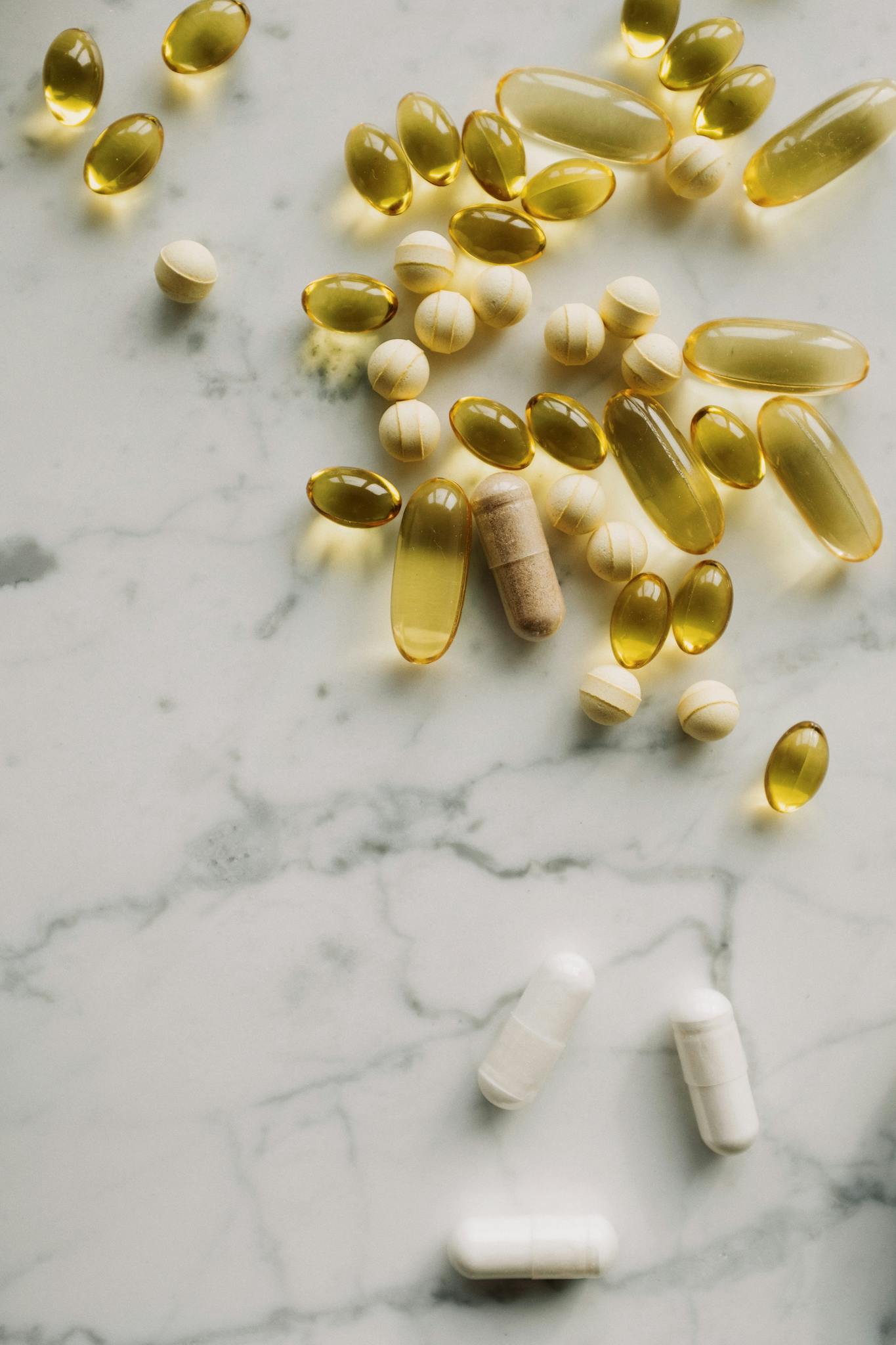 A collection of various pills and supplements displayed on a marble surface, showcasing healthcare essentials.